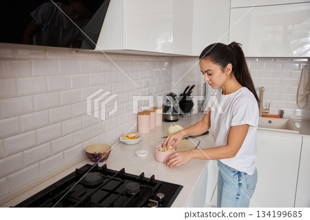 Woman chopping cabbage on a cutting board, preparing a healthy meal at home Woman chopping cabbage on a cutting board, preparing a healthy meal at home 134199685