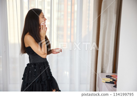 Woman applying facial powder with puff before an event, focusing on beauty and preparation Woman applying facial powder with puff before an event, focusing on beauty and preparation 134199795