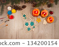Painted wooden toy Christmas tree with brushes, paints, spruce branches, pinecones and candles on table 134200154