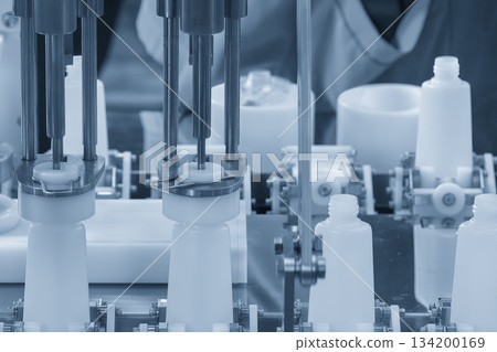 The empty healthcare bottles on the conveyor belt for filling process in blue tone scene. The empty healthcare bottles on the conveyor belt for filling process in blue tone scene. 134200169