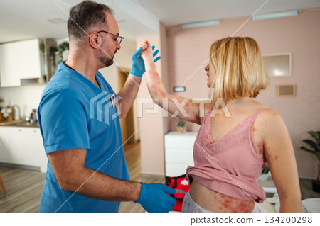 Healthcare professional examining woman showing skin rash outbreak 134200298