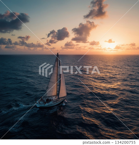 Sailboat sailing on ocean water during a colorful cloudy sunset creating a romantic mood. Sailboat cruising at sunset with a couple on board Sailboat sailing on ocean water during a colorful cloudy sunset creating a romantic mood. Sailboat cruising at sunset with a couple on board 134200755