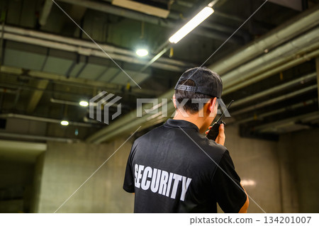 Rear view of a security guard patrolling the parking lot 134201007