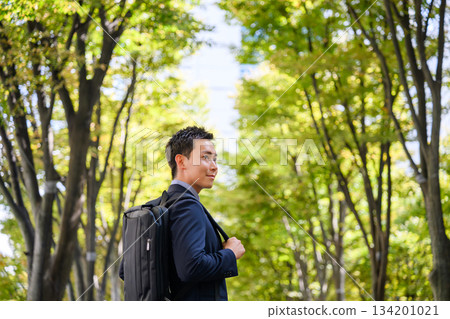 Businessman walking along a green road 134201021