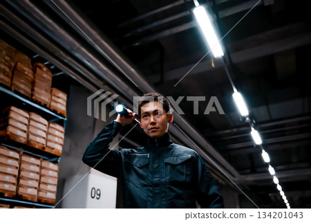 Security guard with flashlight in warehouse Security guard with flashlight in warehouse 134201043