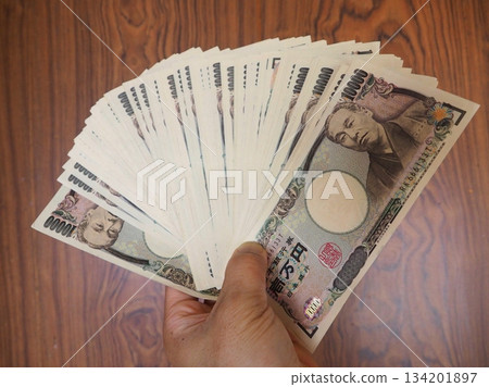 A man spreading out a stack of bills 134201897