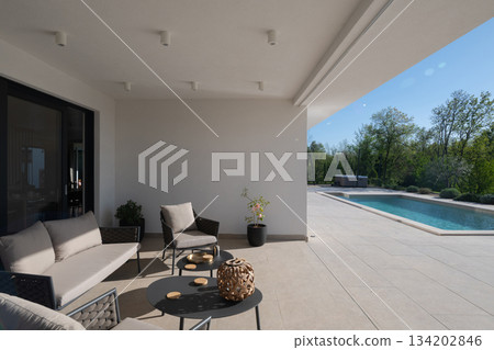 Modern luxury villa with pool, terrace, and minimalist architecture on a sunny day. Clean lines, large windows, and outdoor living spaces create a stylish contemporary home setting 134202846