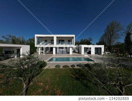 Modern luxury villa with pool, terraces, and clean minimalist architecture captured by drone. Bright sunny day, surrounding greenery, and contemporary outdoor living areas Modern luxury villa with pool, terraces, and clean minimalist architecture captured by drone. Bright sunny day, surrounding greenery, and contemporary outdoor living areas 134202889