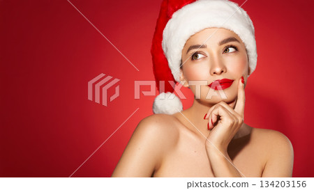 Girl in Santa Hat over holiday red Background Girl in Santa Hat over holiday red Background 134203156