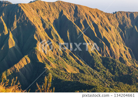 Steep mountain ridges glowing golden on Pergasingan Hill Lombok. 134204661