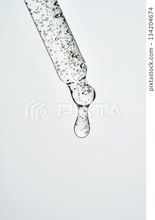 Dropping cosmetic serum from glass pipette applicator 134204674