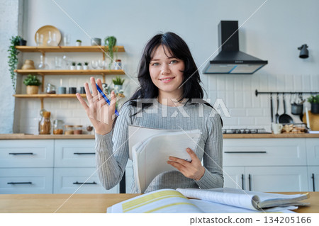 Webcam portrait female university student, sitting at home at the table with textbooks Webcam portrait female university student, sitting at home at the table with textbooks 134205166