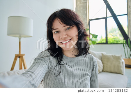 Selfie portrait happy beautiful young woman in home interior 134205182