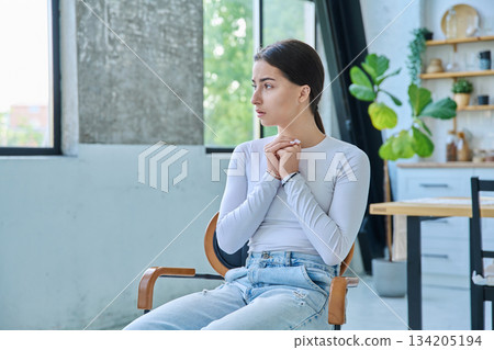 Sad upset teenager girl sitting at home in living room 134205194