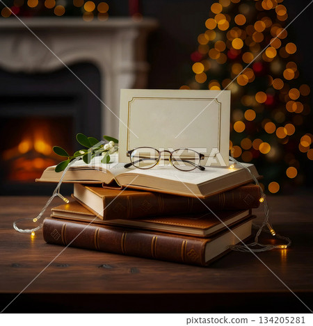 stack of old books with an open page, glasses and a blank card against a fireplace and tree background stack of old books with an open page, glasses and a blank card against a fireplace and tree background 134205281