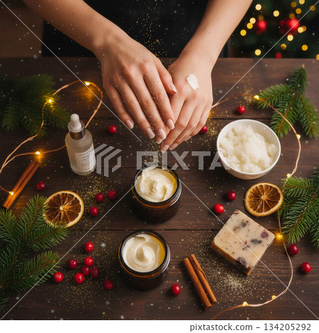 hands applying cream to the skin against a background of natural cosmetics, christmas berries, and pine branches hands applying cream to the skin against a background of natural cosmetics, christmas berries, and pine branches 134205292