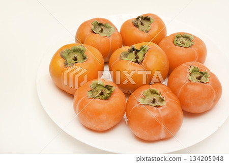 Orange persimmon fruits. Ripe persimmon on a plate. 134205948