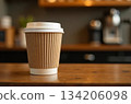 Disposable coffee cup standing on wooden counter in cafe 134206098