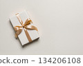 White gift box with golden ribbon on neutral background 134206108
