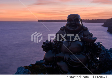 Buddha figure on some rocks, in the sunset, on the sea Buddha figure on some rocks, in the sunset, on the sea 134206719