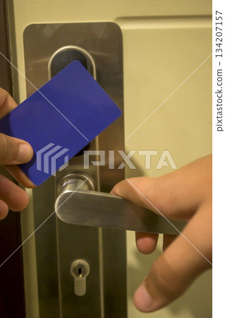 A hand holding a blue card key close to a hotel door lock, key electronic lock, hotel room, holidays in mallorca, spain A hand holding a blue card key close to a hotel door lock, key electronic lock, hotel room, holidays in mallorca, spain 134207157