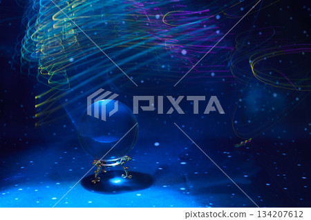 Mystical Crystal Sphere. A crystal ball under swirling colorful light streaks and a starry backdrop. 134207612