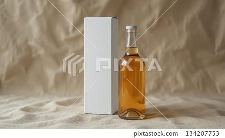 Elegant Glass Bottle Filled With Amber Liquid Beside a Plain White Box on a Textured Surface Elegant Glass Bottle Filled With Amber Liquid Beside a Plain White Box on a Textured Surface 134207753