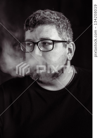 Young Caucasian man smoking an electronic cigarette portrait. Young Caucasian man smoking an electronic cigarette portrait. 134208019