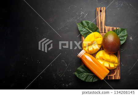 Fresh mango exotic tropical fruit juice smoothie bowl cutting board dark background orange copy space 134208145