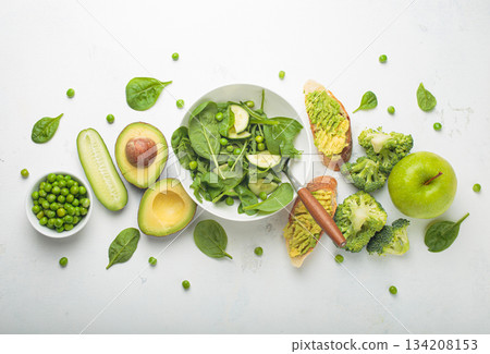 Fresh salad bowl, avocado toasts, raw green vegetables fruit white background top view, diet, vegetarian healthy food Fresh salad bowl, avocado toasts, raw green vegetables fruit white background top view, diet, vegetarian healthy food 134208153