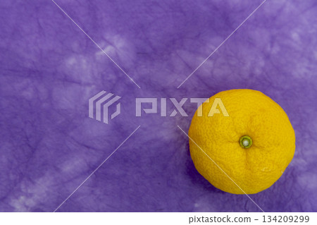 A single yuzu placed on a purple Japanese paper background - an image of the winter solstice and Japanese-style ingredients A single yuzu placed on a purple Japanese paper background - an image of the winter solstice and Japanese-style ingredients 134209299