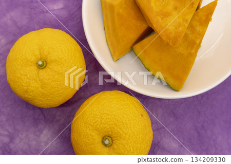 Preparing for the Winter Solstice: Still life of yuzu and cut pumpkin on purple Japanese paper background Preparing for the Winter Solstice: Still life of yuzu and cut pumpkin on purple Japanese paper background 134209330