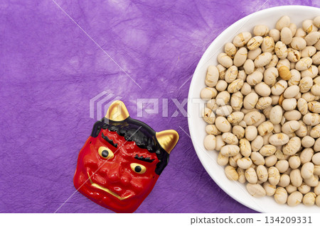 Roasted soybeans and a red demon mask placed on a purple Japanese paper background - an image of the Setsubun festival Roasted soybeans and a red demon mask placed on a purple Japanese paper background - an image of the Setsubun festival 134209331