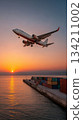 Airplane flying over a harbor at sunset, casting reflections on the water, with colorful shipping containers lining the dock, showcasing transportation and travel dynamics 134211002
