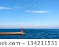 A red navigational marker (lighthouse/beacon) standing against a calm blue sky, sea and horizon 134211531