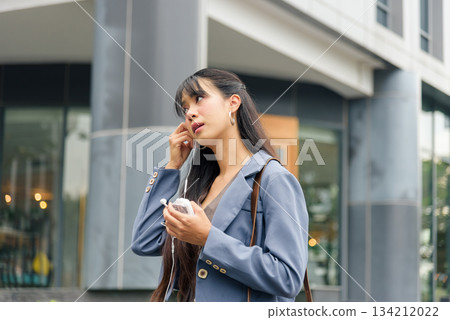 Travel woman, young person enjoying business lifestyle, inserts earphones for work on bustling city street, vibrant outdoor urban setting perfect for modern professionals. Travel woman, young person enjoying business lifestyle, inserts earphones for work on bustling city street, vibrant outdoor urban setting perfect for modern professionals. 134212022
