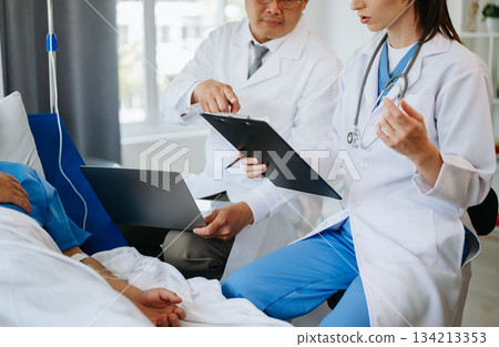 Two doctors talking to a patient lying in his bed  with receiving saline solution 134213353