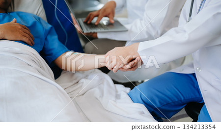 Female doctor holding male patient hand on the bed with receiving saline solution in hospital 134213354