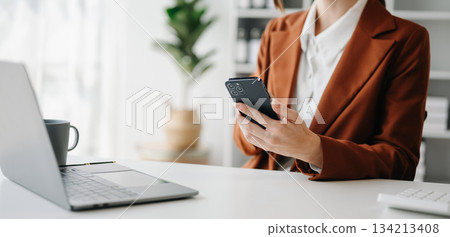 Businesswoman s hands typing on smartphone, tablet and laptop computer Businesswoman s hands typing on smartphone, tablet and laptop computer 134213408