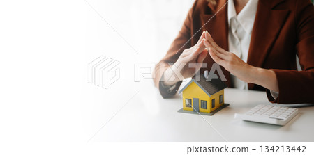 Female real estate agent is use hands to protect red roof for the concept Female real estate agent is use hands to protect red roof for the concept 134213442