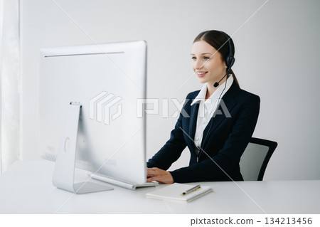 Serious call center operator in wireless headset talking with customer, woman in headphones Serious call center operator in wireless headset talking with customer, woman in headphones 134213456