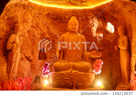 Buddha statue sculpture in a cave of the temple in front of the entrance gate at the Tianshan Grand Canyon, or Kesileya Grand Canyon, is a stunning natural feature in Xinjiang, China. 134213637