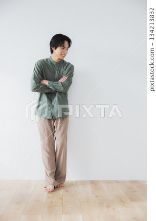 Man standing leaning against a wall Man standing leaning against a wall 134213832