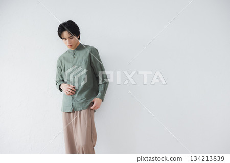 Man standing leaning against a wall 134213839