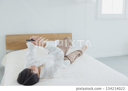 Men watching smartphones in bed Men watching smartphones in bed 134214022