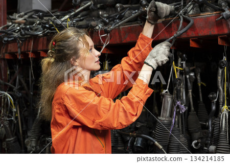 Female technician worker working in garage scrap yard old car part workshop warehouse. 134214185