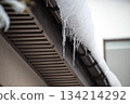 Icicles Hanging From Snow-Covered Roof Edge Create Winter Chill and Quiet Morning Atmosphere 134214292