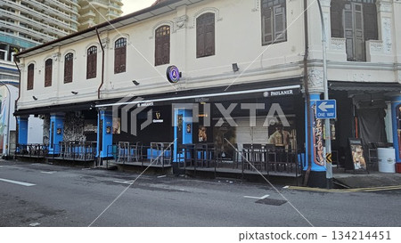 A heritage shophouse from 1927 with arched windows and outdoor bar seating blends classic architecture with modern nightlife, featuring beer signage A heritage shophouse from 1927 with arched windows and outdoor bar seating blends classic architecture with modern nightlife, featuring beer signage 134214451