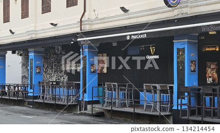 A heritage shophouse from 1927 with arched windows and outdoor bar seating blends classic architecture with modern nightlife, featuring beer signage and vibrant street energy in Singapore urban scen 134214454
