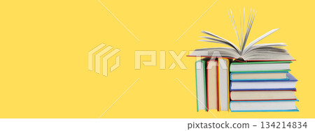 Books are arranged on a yellow background with one open Books are arranged on a yellow background with one open 134214834